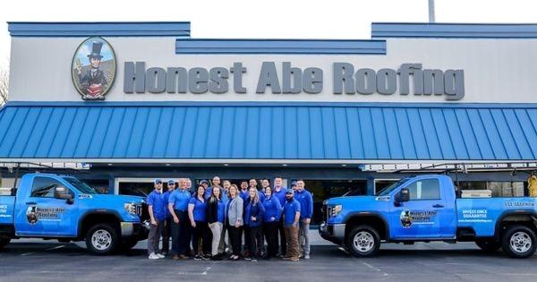 Honest Abe Roofing team standing outside headquarters with branded trucks, roofing franchise opportunity and team culture