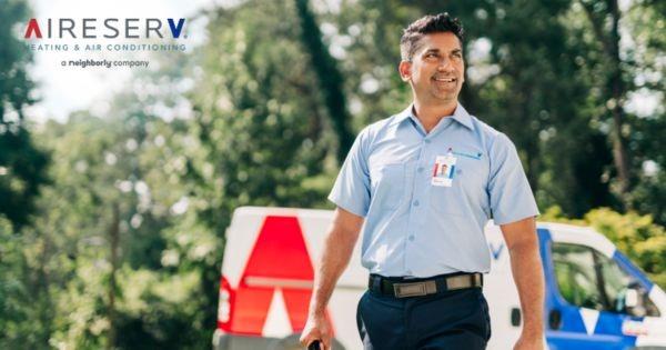 Aire Serv HVAC technician walking beside service van, representing heating and air conditioning franchise opportunity