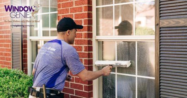 Window Genie franchise technician cleaning residential windows, highlighting exterior cleaning and window washing services