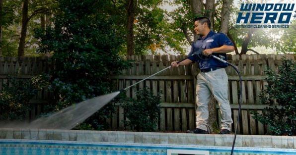 Window Hero franchise technician pressure washing pool deck, highlighting exterior cleaning and power washing services