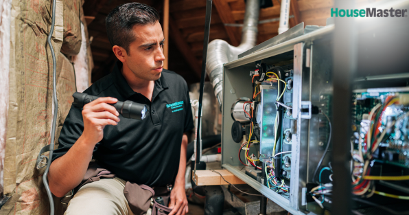 HouseMaster franchise home inspector examining HVAC equipment, highlighting professional home inspection services