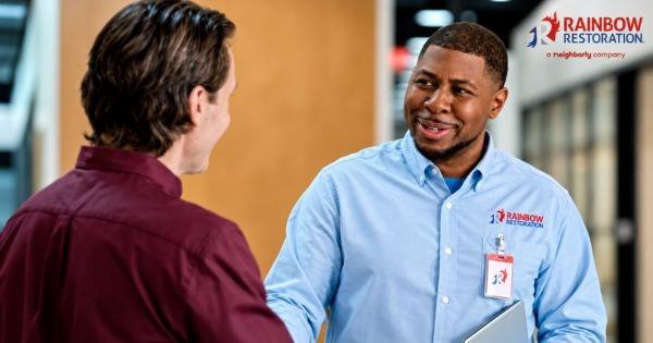 Rainbow Restoration franchise featuring a team member greeting a customer, highlighting professional restoration and cleaning services