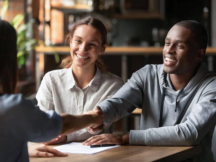 Franchise consultant shaking hands with clients while discussing how to earn money selling franchises