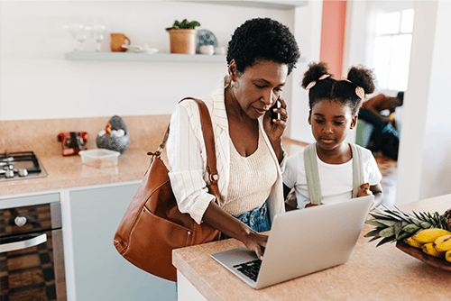 Franchise consultant working from home on a laptop and phone while her daughter stands beside her